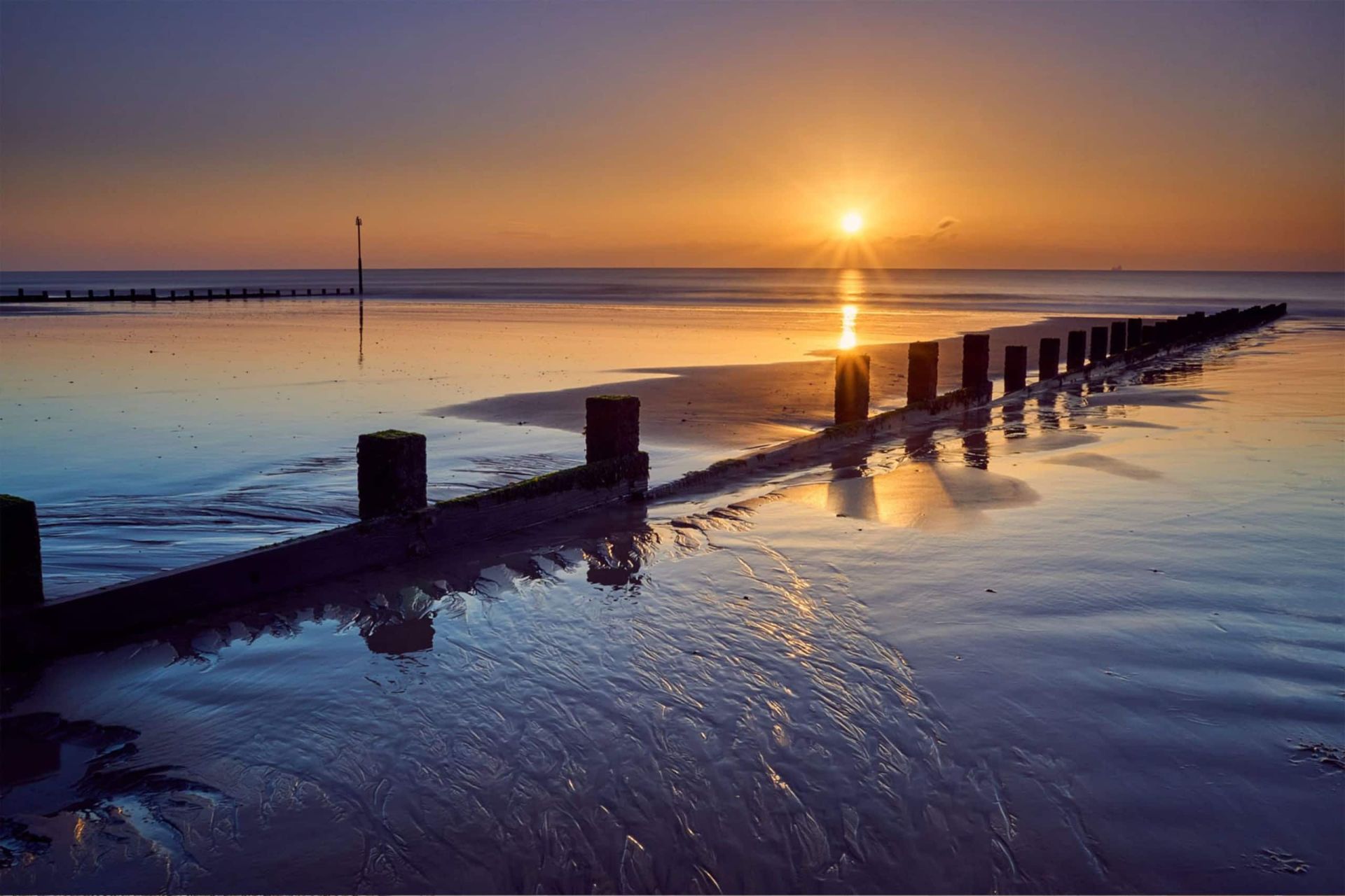 Dymchurch beach at sunset Sunset over the sandy beach and groynes at Dymchurch, Kent